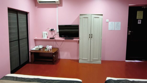 Habitación de hotel con dos camas, un escritorio con computadora, televisión, aire acondicionado y armario.