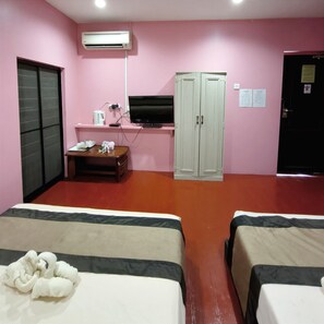 Habitación de hotel con dos camas, un escritorio con computadora, televisión, aire acondicionado y armario.