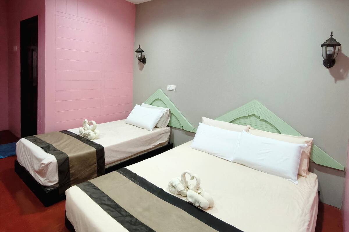 Een hotelkamer met twee bedden, elk met een groen hoofdeinde, witte beddengoed en een handdoek op het bed.