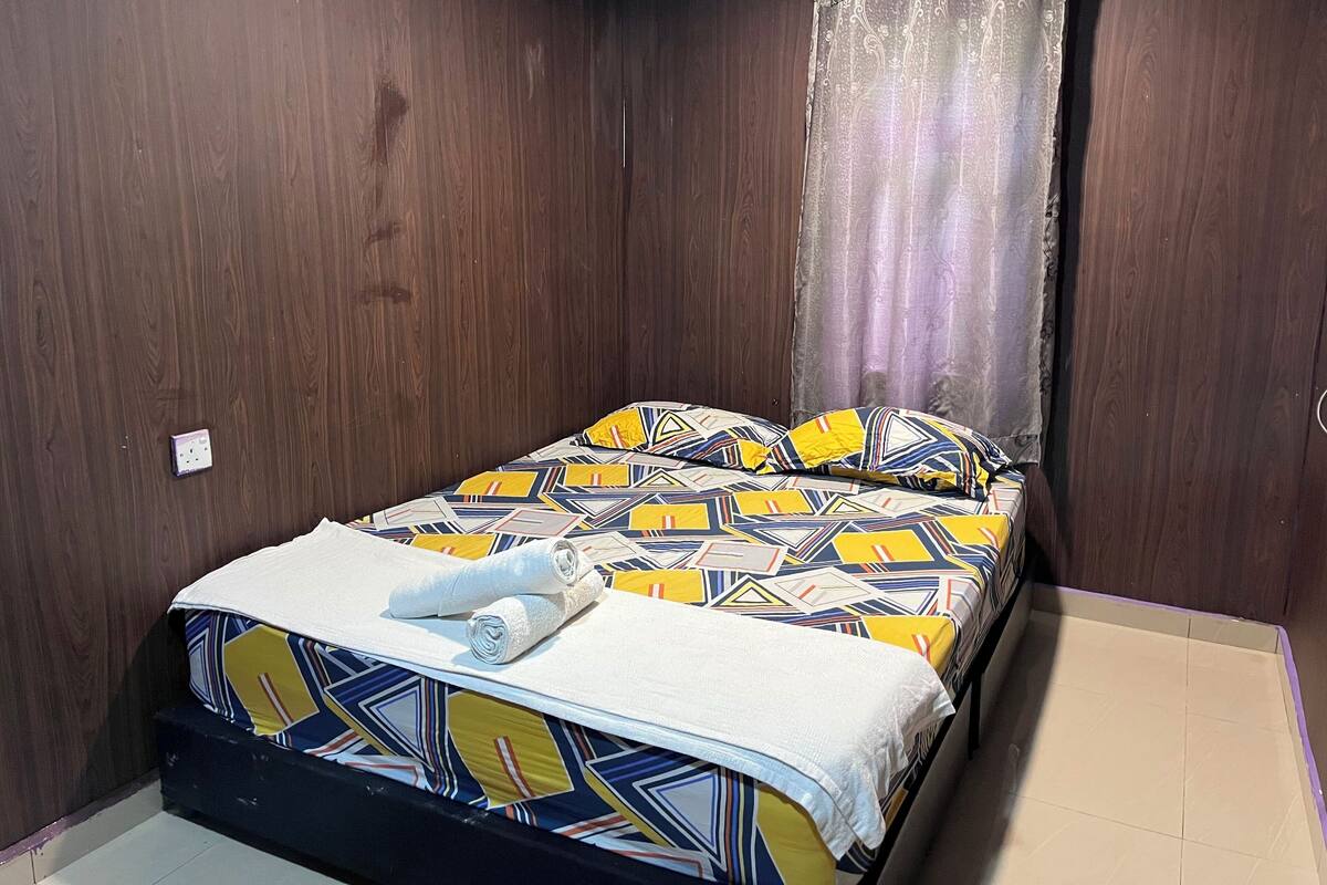 Een slaapkamer met een bed, gordijn en een stopcontact.