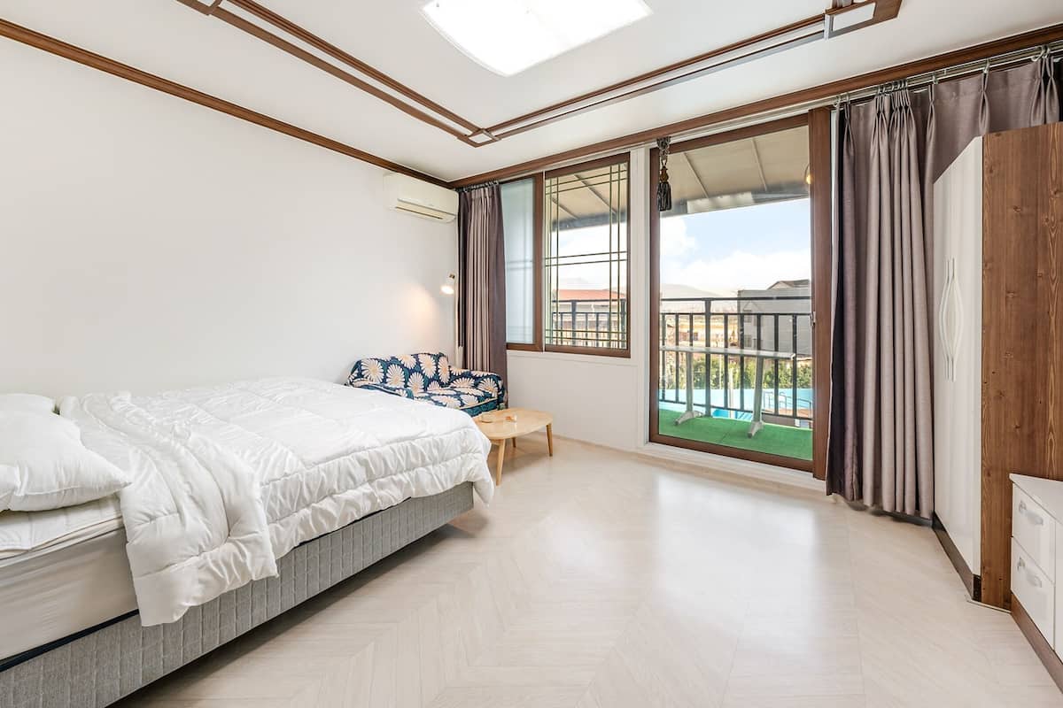 Ein Schlafzimmer mit einem Bett, einem kleinen Tisch und Blick auf einen Balkon.