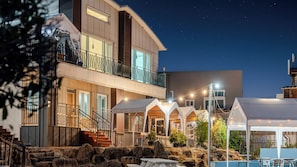 A multi-story building with a balcony, outdoor seating area, and a pool.