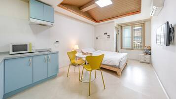 A compact room with a bed, a small table with chairs, a microwave, and a window with a view.