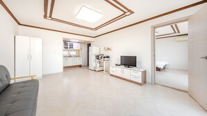 Un apartamento moderno y bien iluminado con kitchenette, televisor y sofá gris.