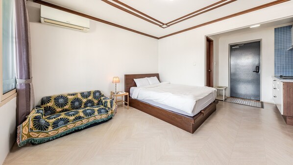 Un dormitorio con cama, sofá, mesita de noche y una puerta.