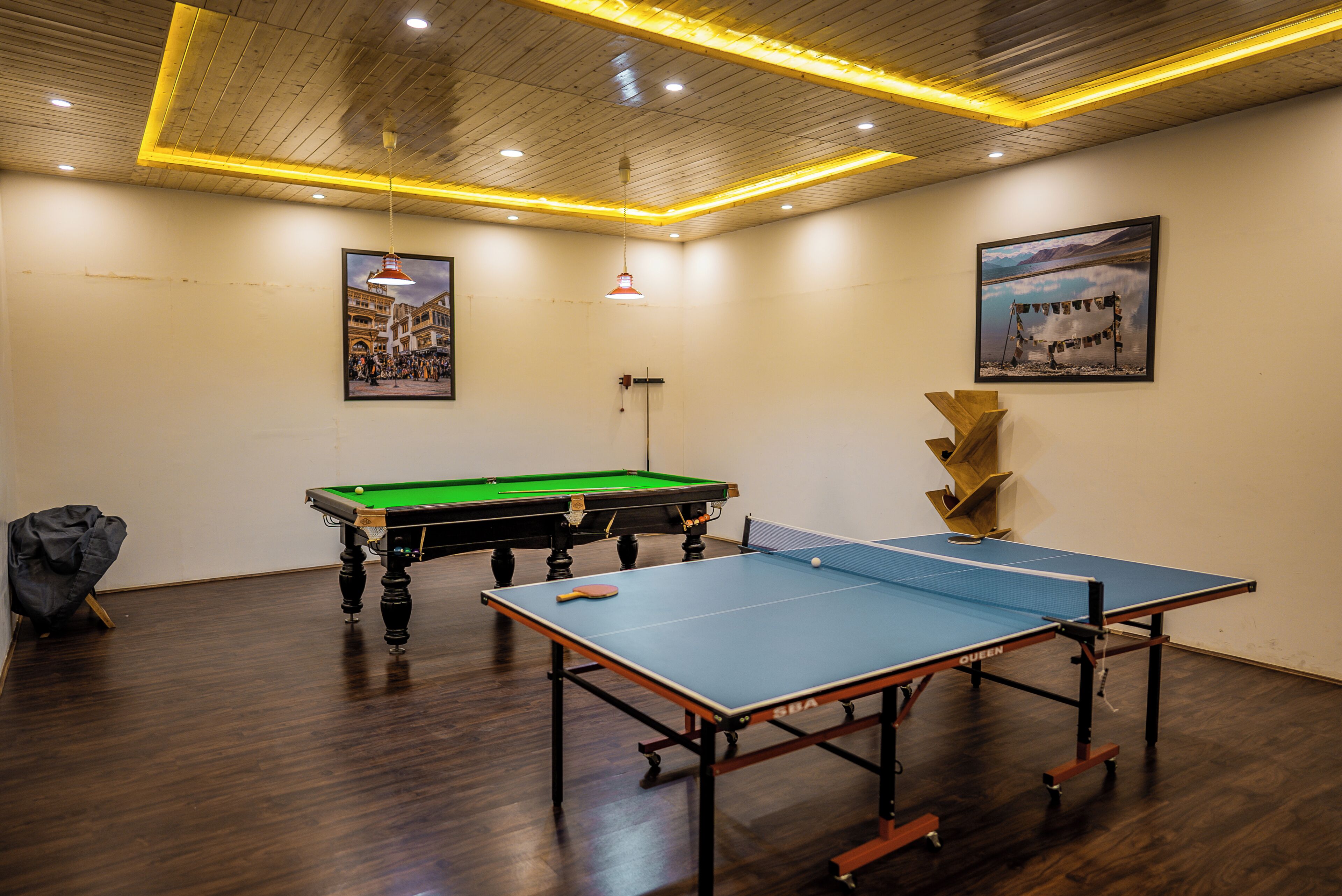 A room with a pool table, a ping pong table, and a billiards table.