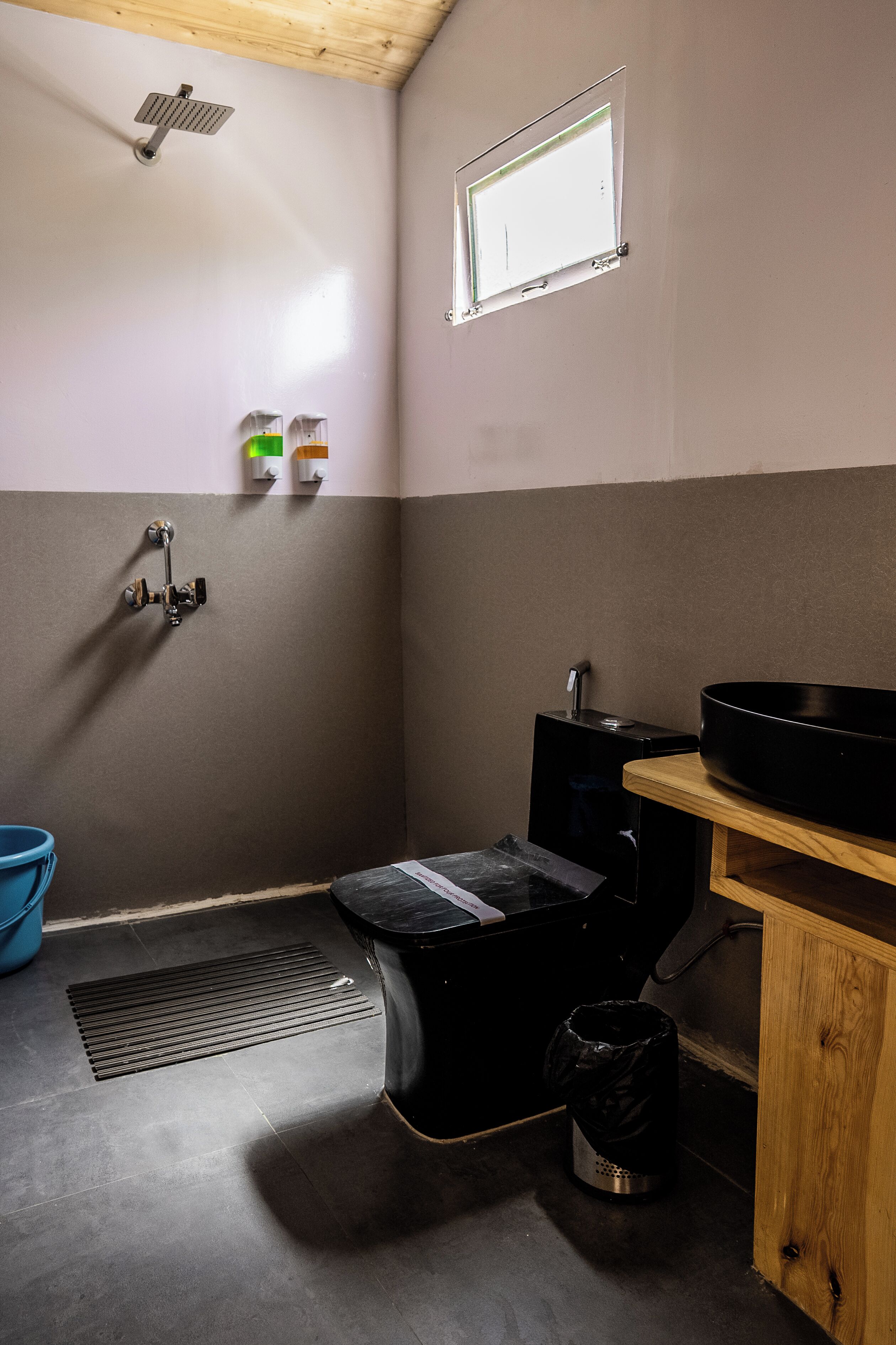 A bathroom with a shower, toilet, sink, and a window.