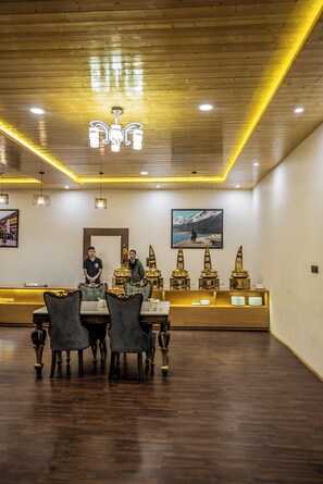 A dining area with wooden tables and chairs, a chandelier, and decorative items on a counter.