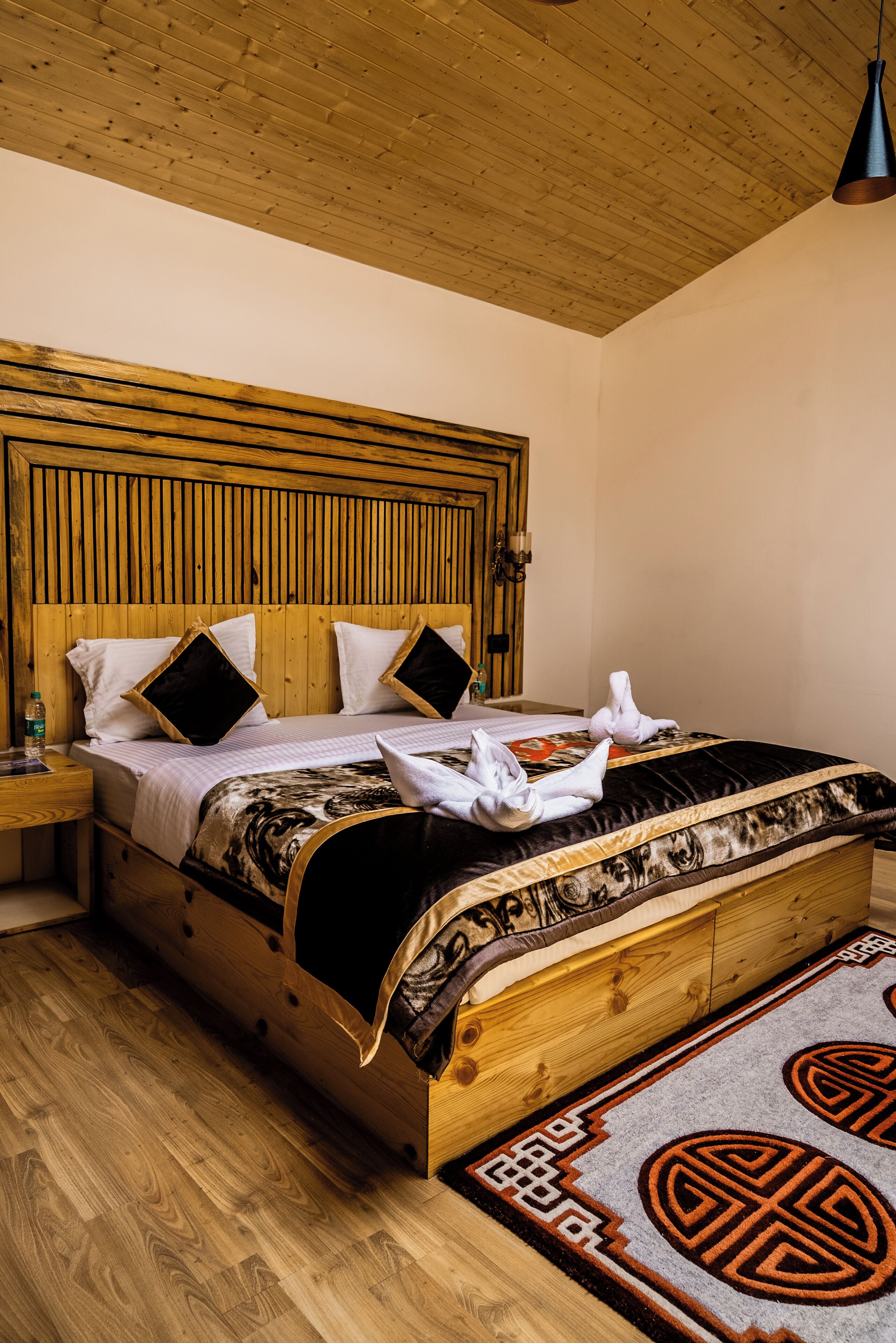 Un lit en bois avec une tête de lit, une table de chevet et un tapis à motifs.