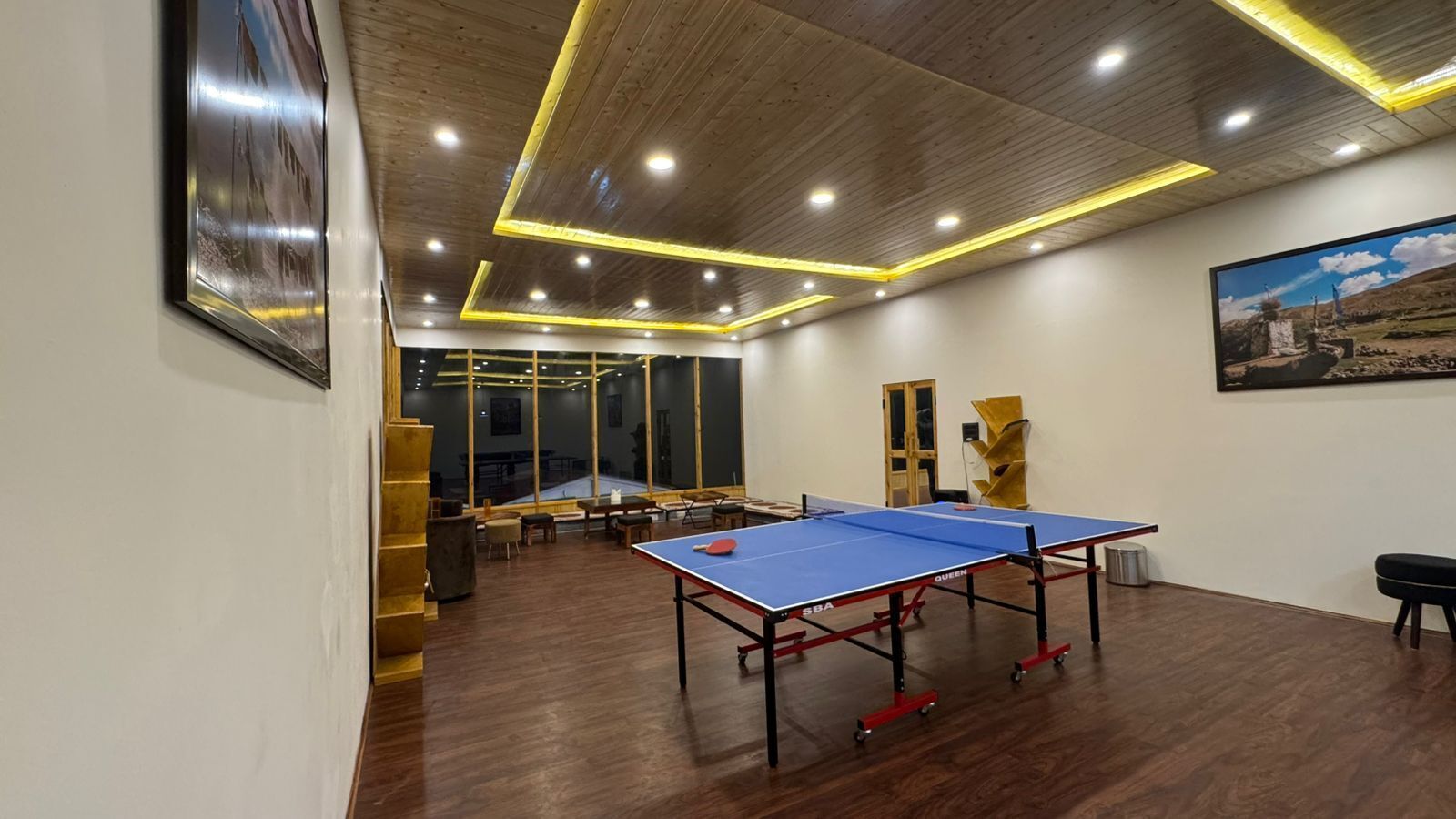 Una habitación con mesa de ping pong, suelo de madera y un amplio ventanal.