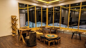 Een kamer met een houten vloer, een ronde tafel met stoelen, een bank en een boekenkast.