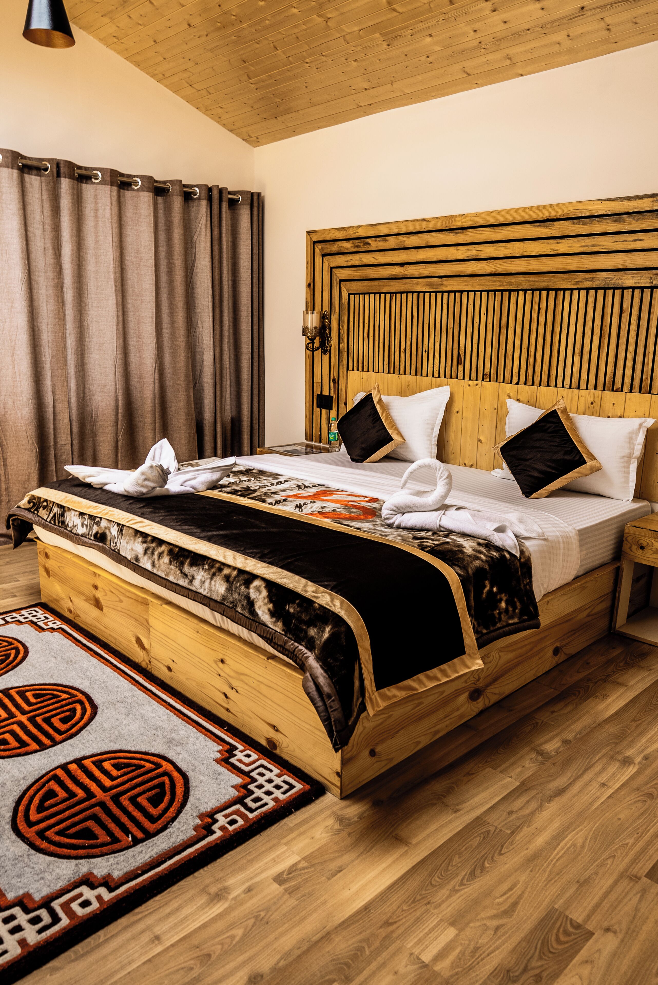 Uma cama de madeira com cabeceira, mesa de cabeceira e um tapete estampado.
