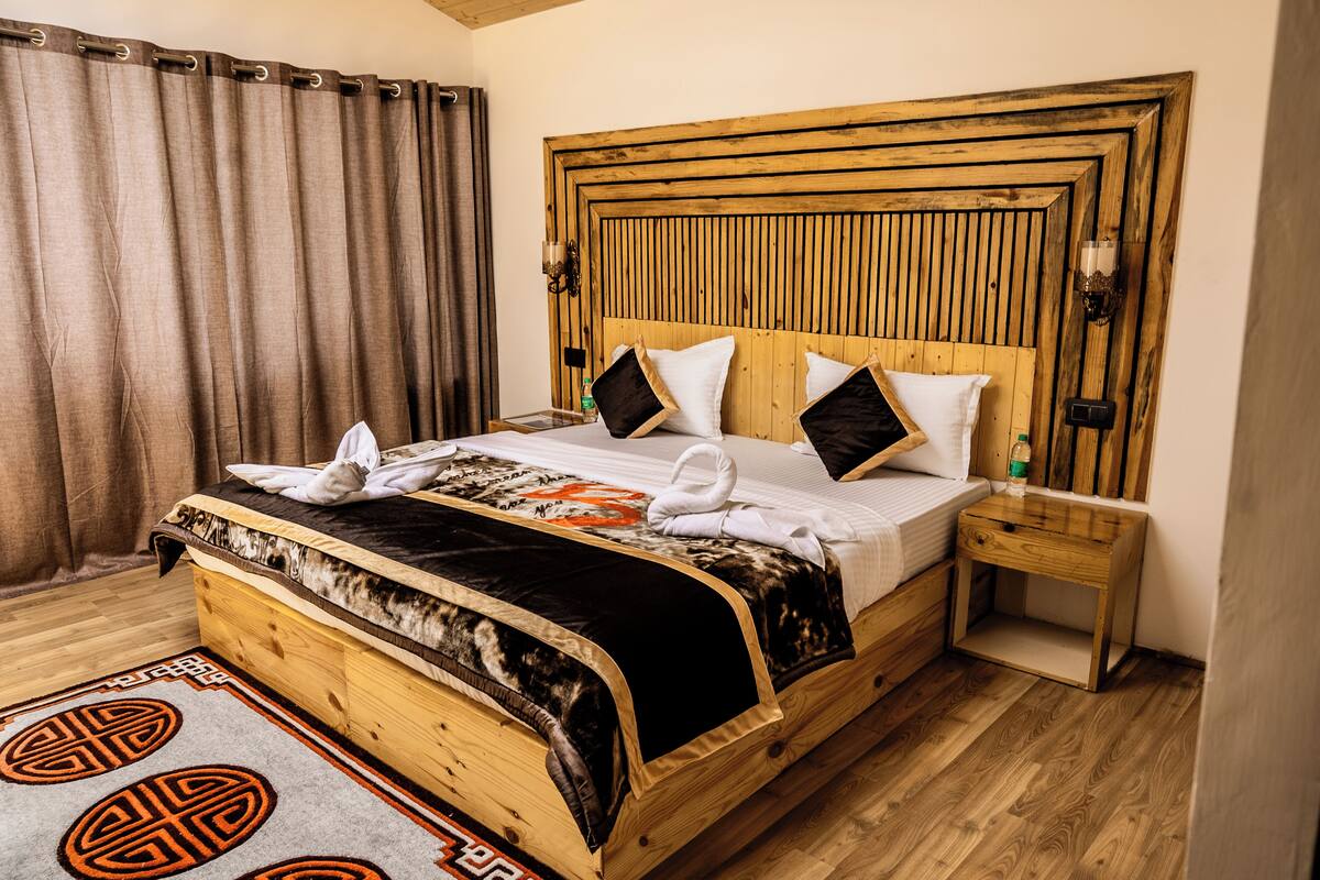A wooden bed with a headboard, a bedside table, and a patterned rug.