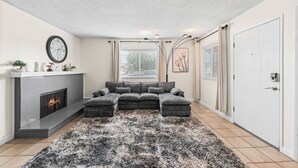 Una sala de estar con un sofá modular, chimenea y un tapete grande.