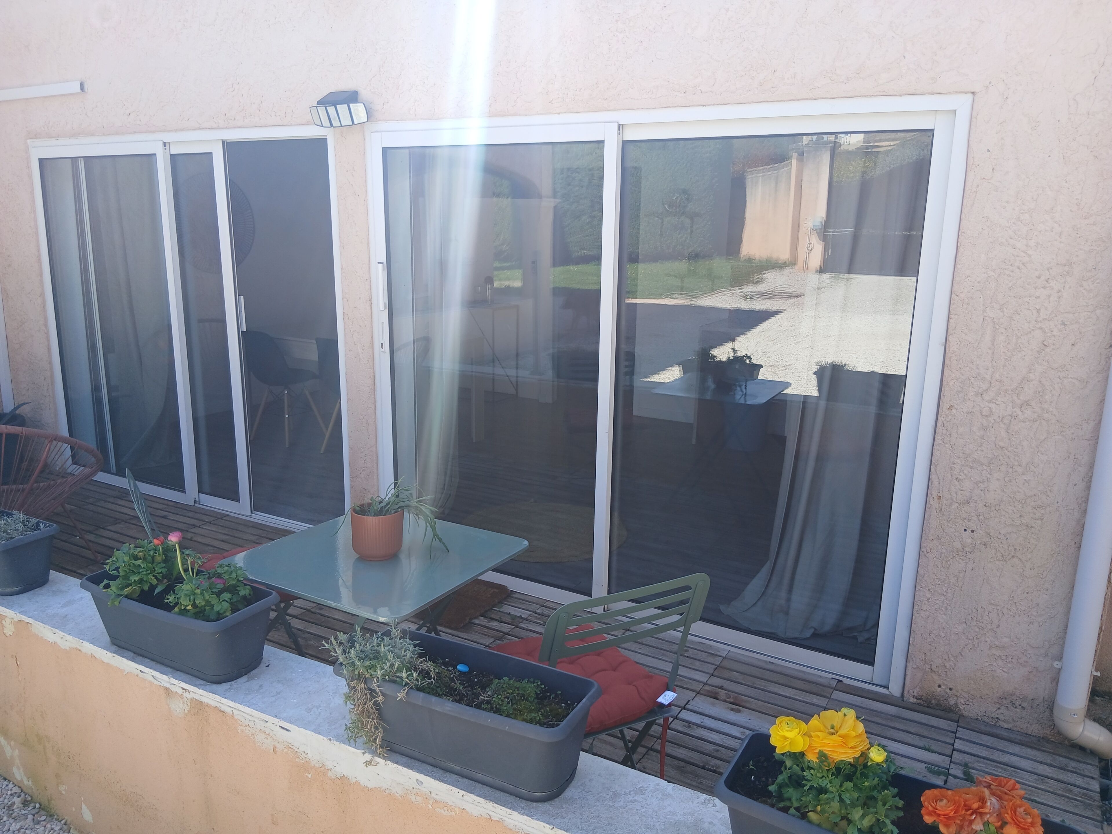 A patio area with a table, chairs, and potted plants.