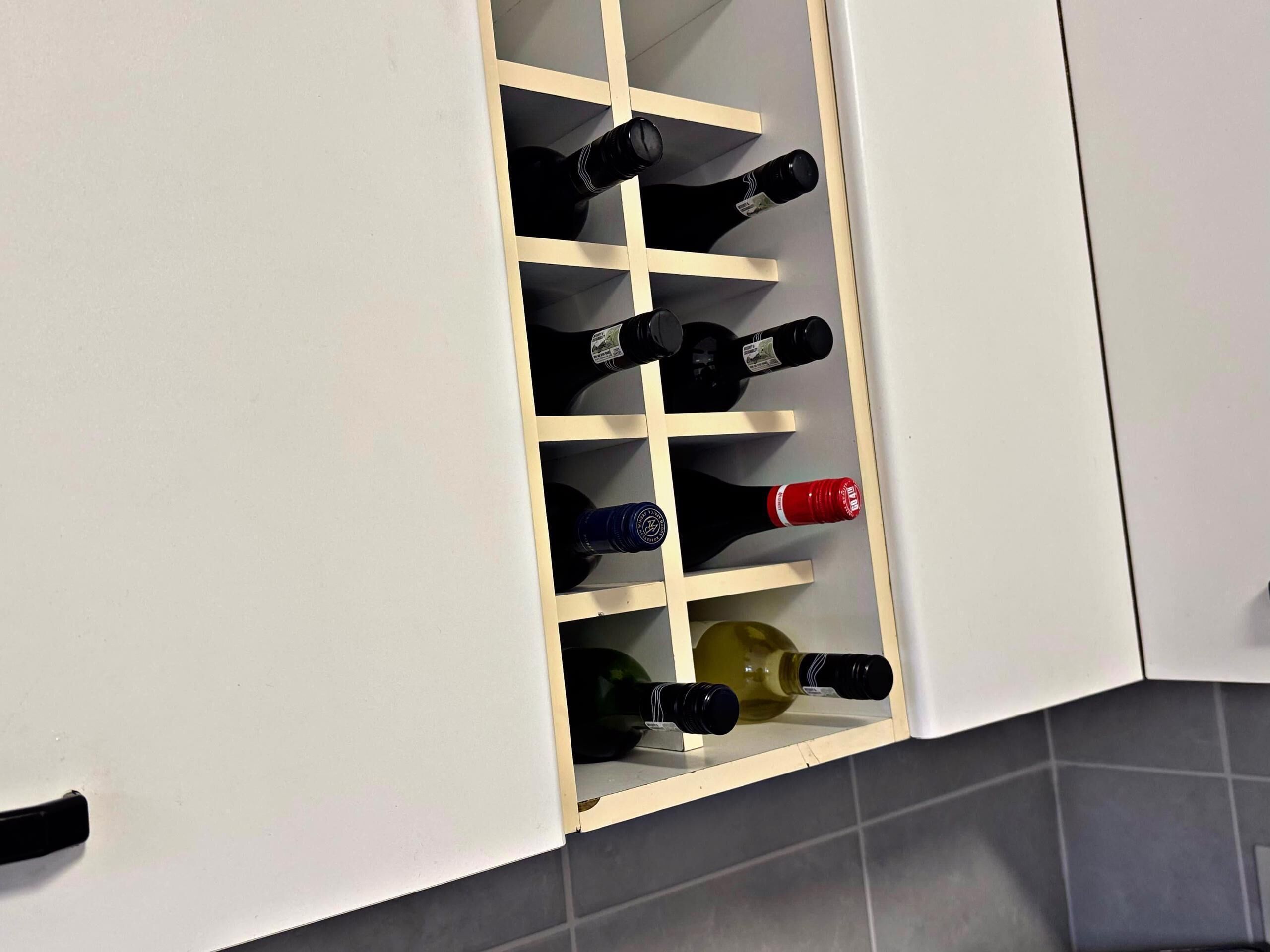 A wine rack with multiple bottles in a kitchen setting.