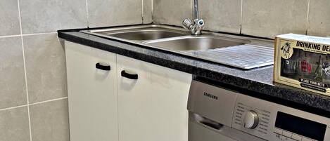 Una cocina compacta con lavavajillas integrado y un lavabo.
