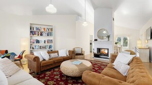 A living room with a fireplace, sofas, a round coffee table, and a bookshelf.