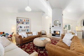 A living room with a fireplace, sofas, a round coffee table, and a bookshelf.