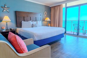 A hotel room with a large bed, two bedside tables, a nightstand, a chair, a balcony with a view, and a star decoration on the wall. - Caravelle 1514 (Myrtle Beach)