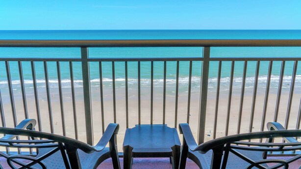 Ein Balkon mit Blick auf Strand und Meer.