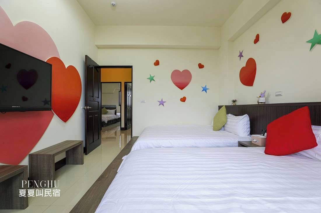 A hotel room with two beds, a TV, and a door leading to another room.