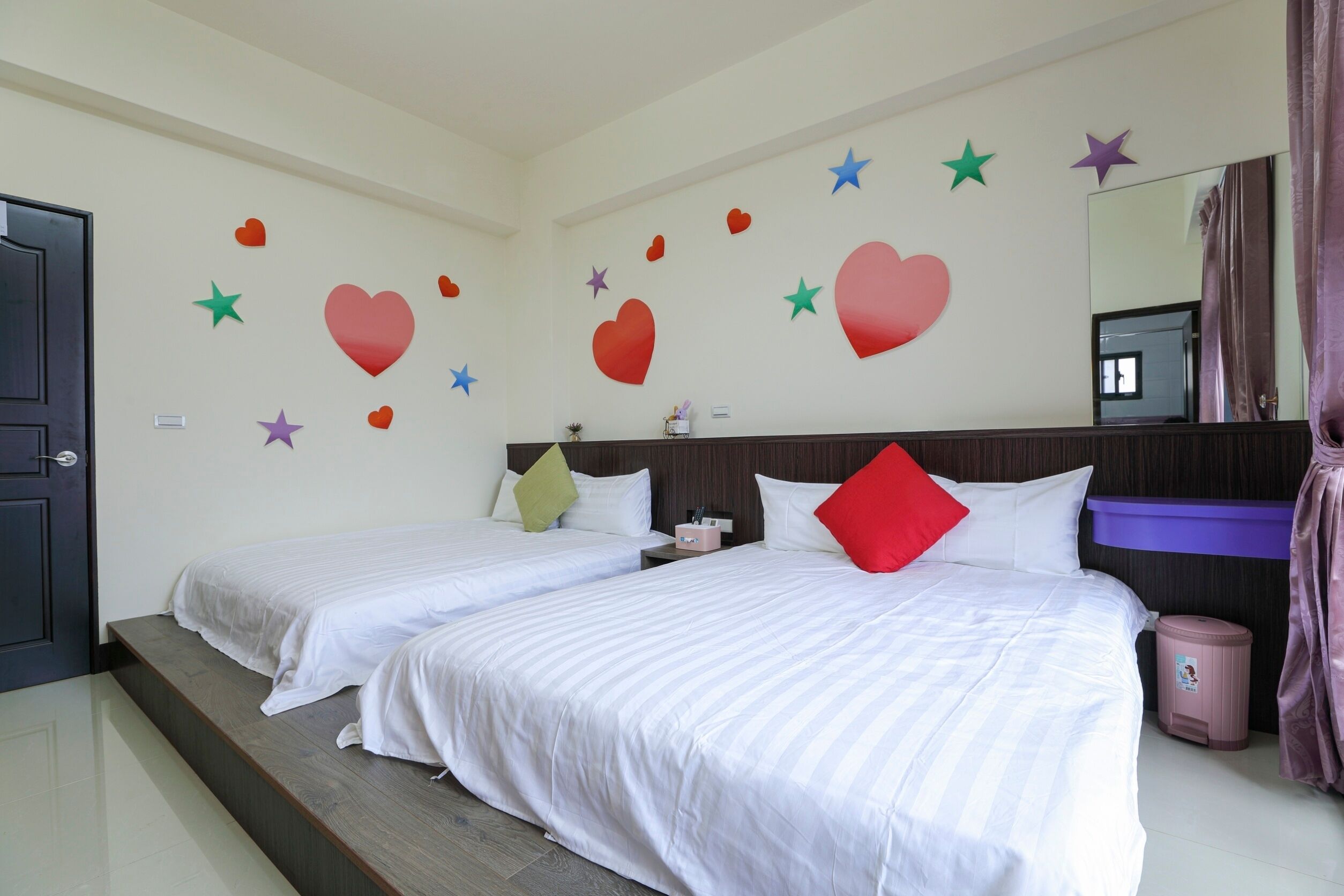 A hotel room with two beds, a large mirror, and decorative wall stickers.