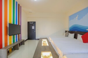 Habitación de hotel con cama, televisor montado en la pared, puerta y pared con rayas de colores.