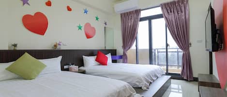 Una habitación de hotel con dos camas, un ventanal con cortinas, un televisor y adhesivos decorativos en la pared.