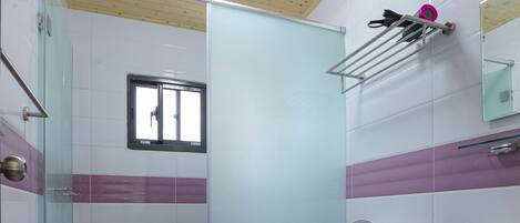 Een badkamer met een zwart-wit geruite vloer, toilet, douche met glazen deur en een wastafel met spiegel erboven.