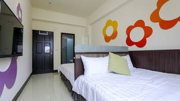 A hotel room with a bed, a TV, and a door.