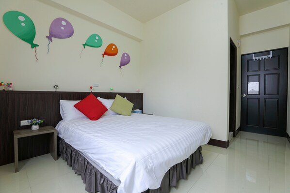 Una habitación de hotel con una cama bien hecha, una mesita de noche con una planta y una pared decorada con globos de colores.
