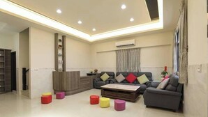 A modern living room with a sofa, coffee table, and colorful stools. - XIA XIA JIAO HOMESTAY (Magong)