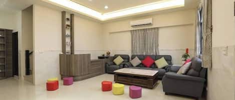 A modern living room with a sofa, coffee table, and colorful stools.