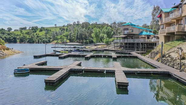 A lakeside property with docked boats, a wooden pier, and a building with a green roof. - Drifters Wake & Wine Getaway (Lake Tulloch)