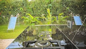 A kitchen with a gas stove, a sink, and a view of a lush garden. - Tilawa La Fortuna Glamping (La Fortuna)