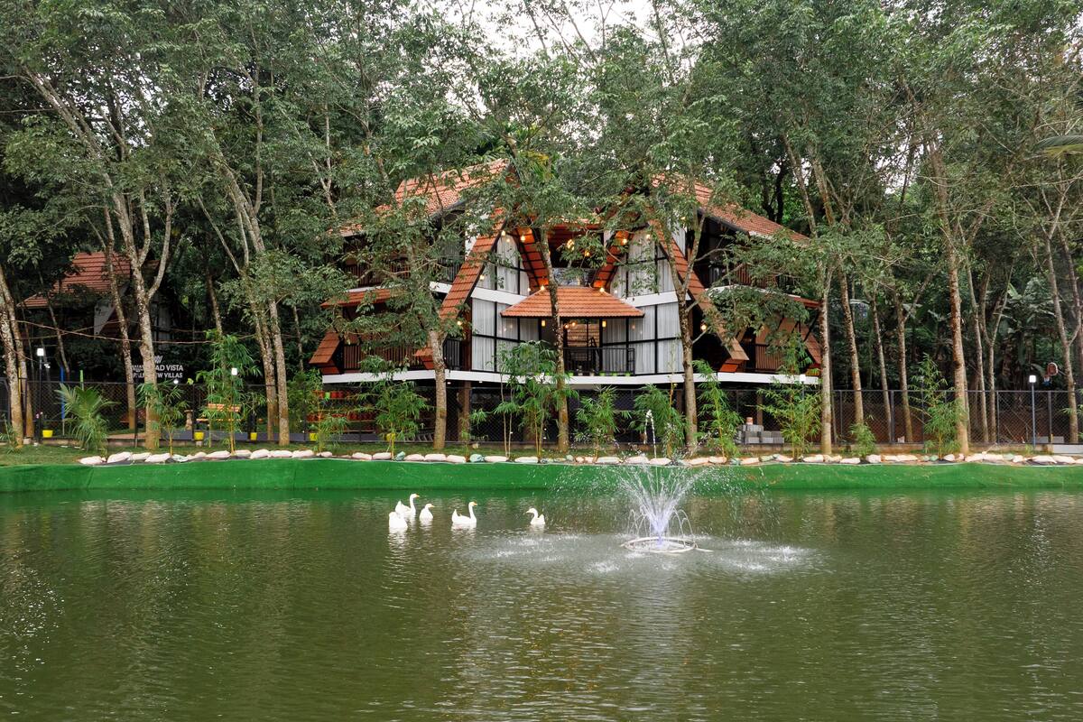 A building with a traditional architectural style, surrounded by a pond with swans and a fountain.