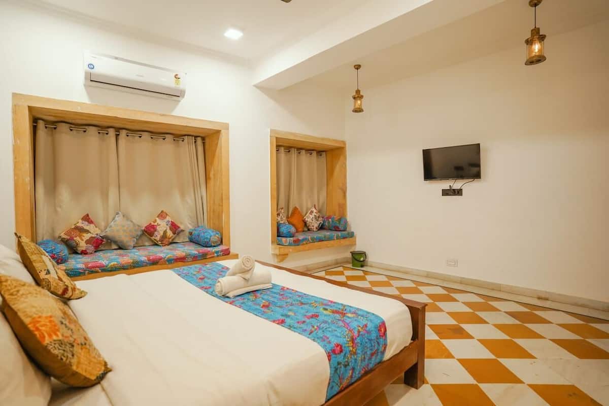 A bedroom with two beds, a TV, and an air conditioning unit.