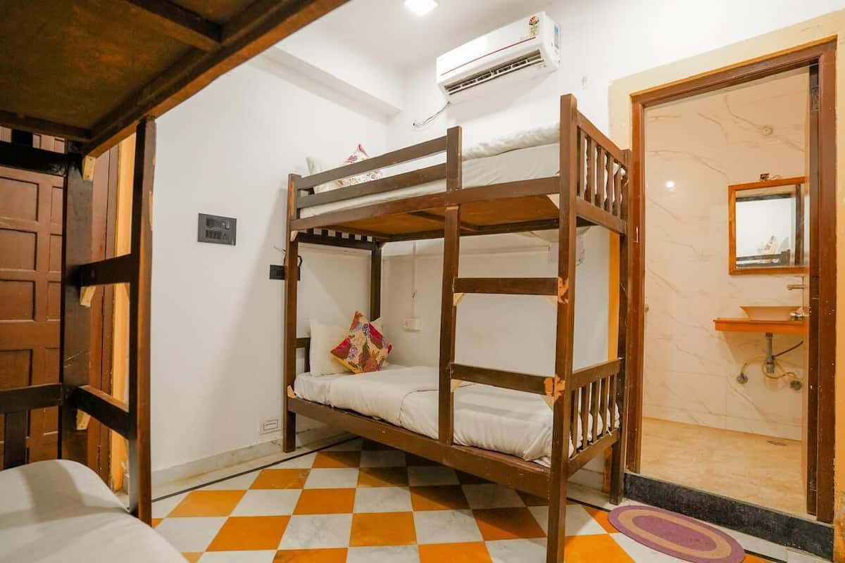A bunk bed room with a checkered floor, a wooden door, and a bathroom with a marble wall and sink.