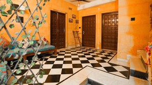Una habitación con piso a cuadros, dos puertas de madera, un ventilador de techo y una lámpara.