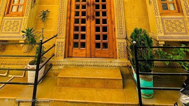Un edificio con detalles arquitectónicos ornamentales, incluyendo varias ventanas con marcos de madera y elementos decorativos.
