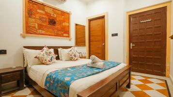 A neatly made bed with a floral bedspread, a large tapestry on the wall, and a checkered floor.