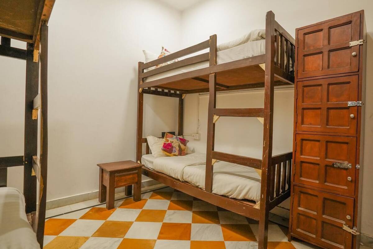 A bunk bed with a wooden frame, a small bedside table, and a checkered floor.
