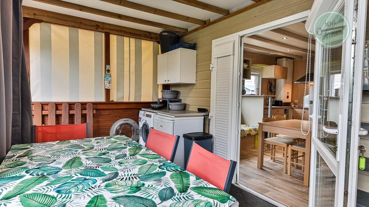 Une pièce compacte comprenant un lit, un lave-linge, une petite kitchenette et un coin repas.