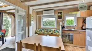 Een compacte camperkeuken met een eethoek, houten kastjes en een raam dat natuurlijk licht binnenlaat.