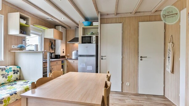Een kleine keuken met een houten tafel, kastjes en een magnetron.