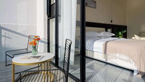 Une chambre à coucher moderne avec un lit, une table de chevet, une chaise et un vase rempli de fleurs.