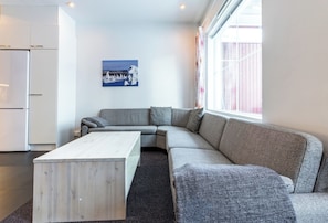 Un salon moderne avec un canapé gris, une table basse en bois et un tableau accroché au mur.