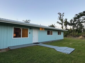 A light blue single-story house with a front door, two windows, and a small porch area.