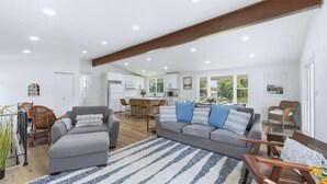 A spacious living room with a grey sofa, wicker chairs, and a striped rug.